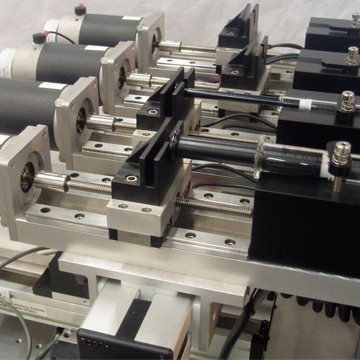 Automated industrial machine with multiple metal clamps and linear rails on a workbench