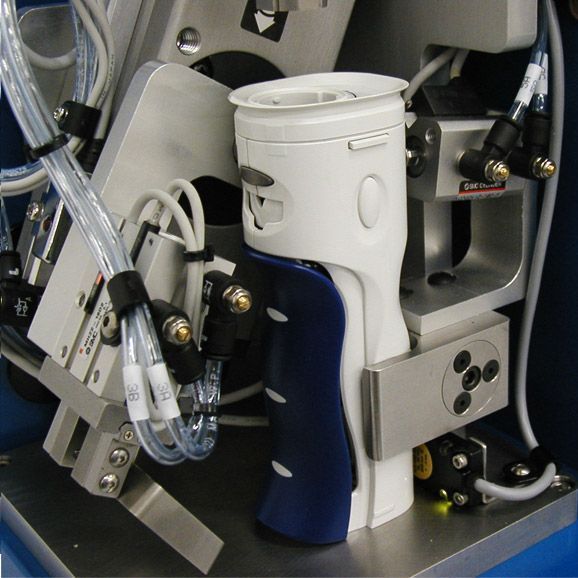Close-up of a white robotic device with cables and metal components inside machinery
