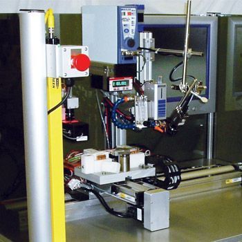 Industrial robot arm on a factory machine with control panels and yellow safety post