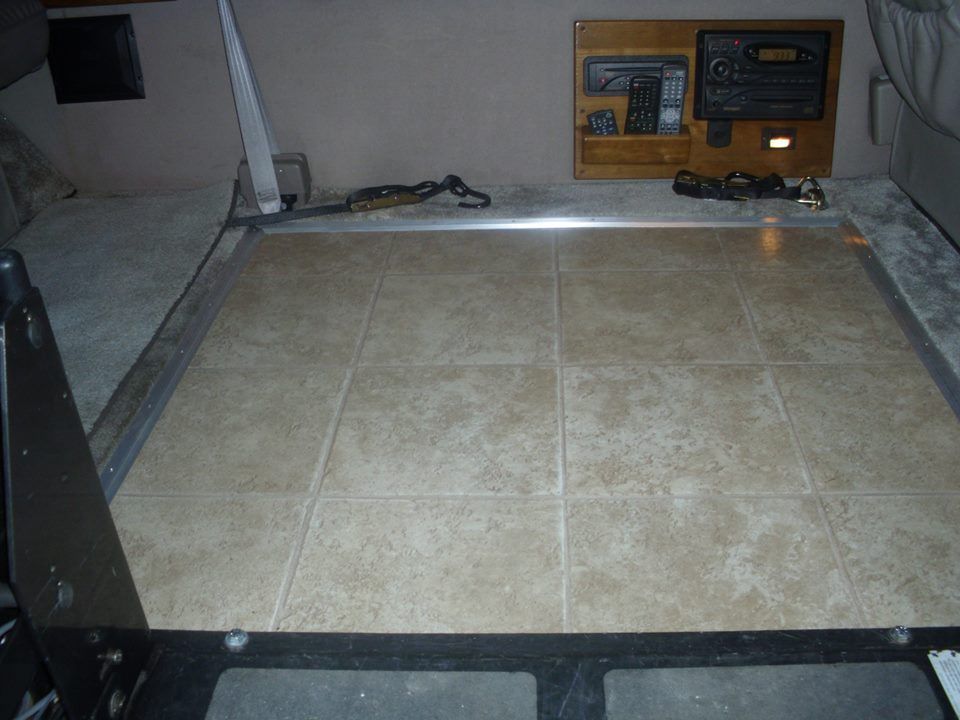 A tiled floor in a room with a tv on the wall