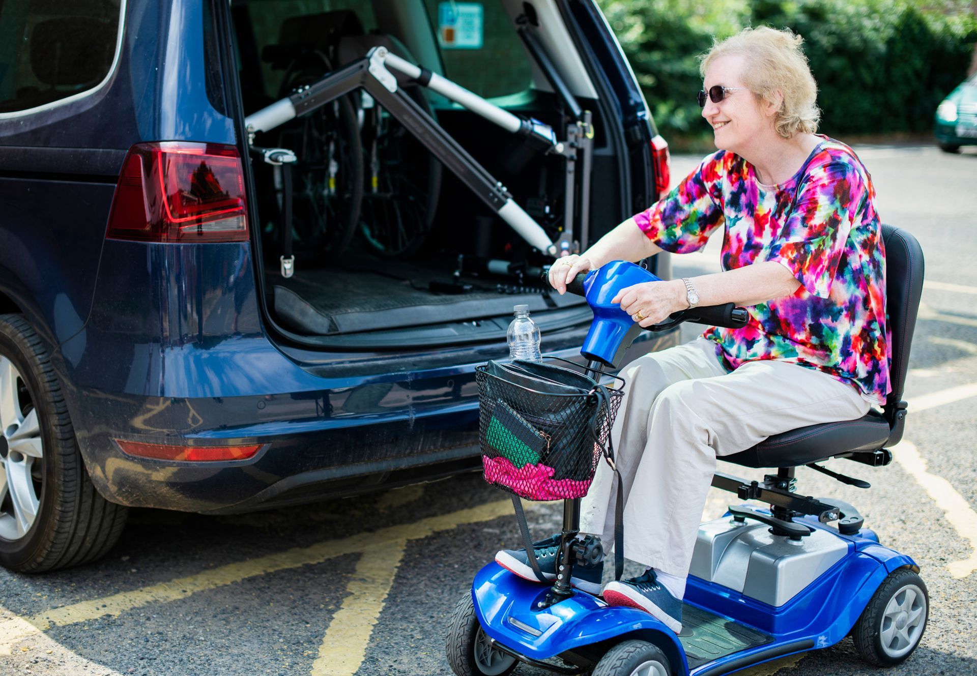A Woman is Sitting on a Mobility Scooter in Front of a Car