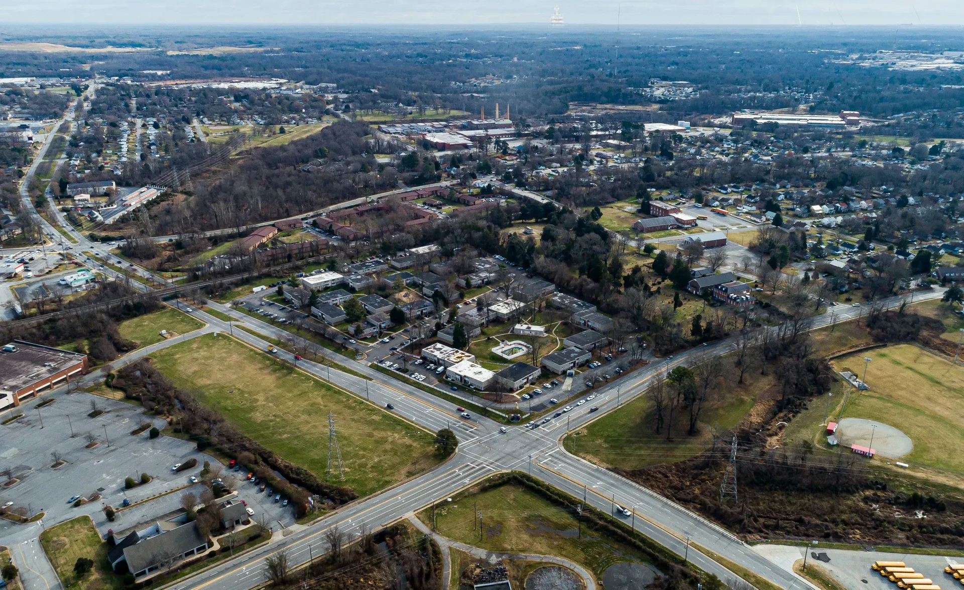 Aerial view of a suburban area with roads, buildings, and open fields.