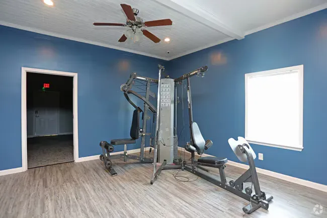 Gym with treadmill, elliptical, and stationary bike. Blue wall, wood-look floor at New Irving Heights, which offers apartments for rent in Greensboro, NC.