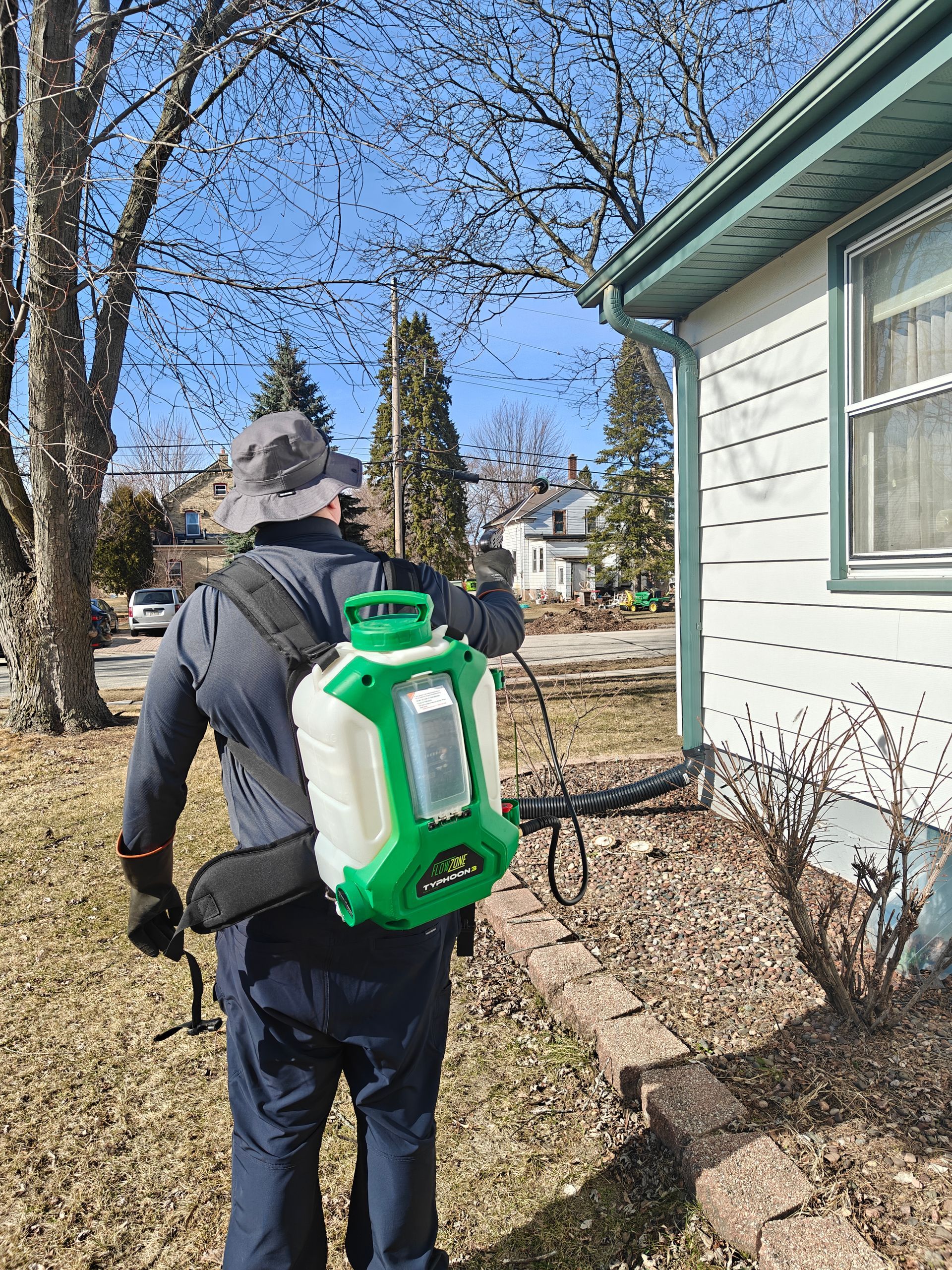 Pest control worker in protective suit sprays insecticide in a kitchen.