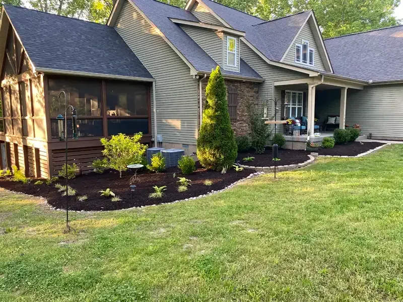 Suburban house with stone and siding exterior, screened porch, landscaped front yard, and green lawn