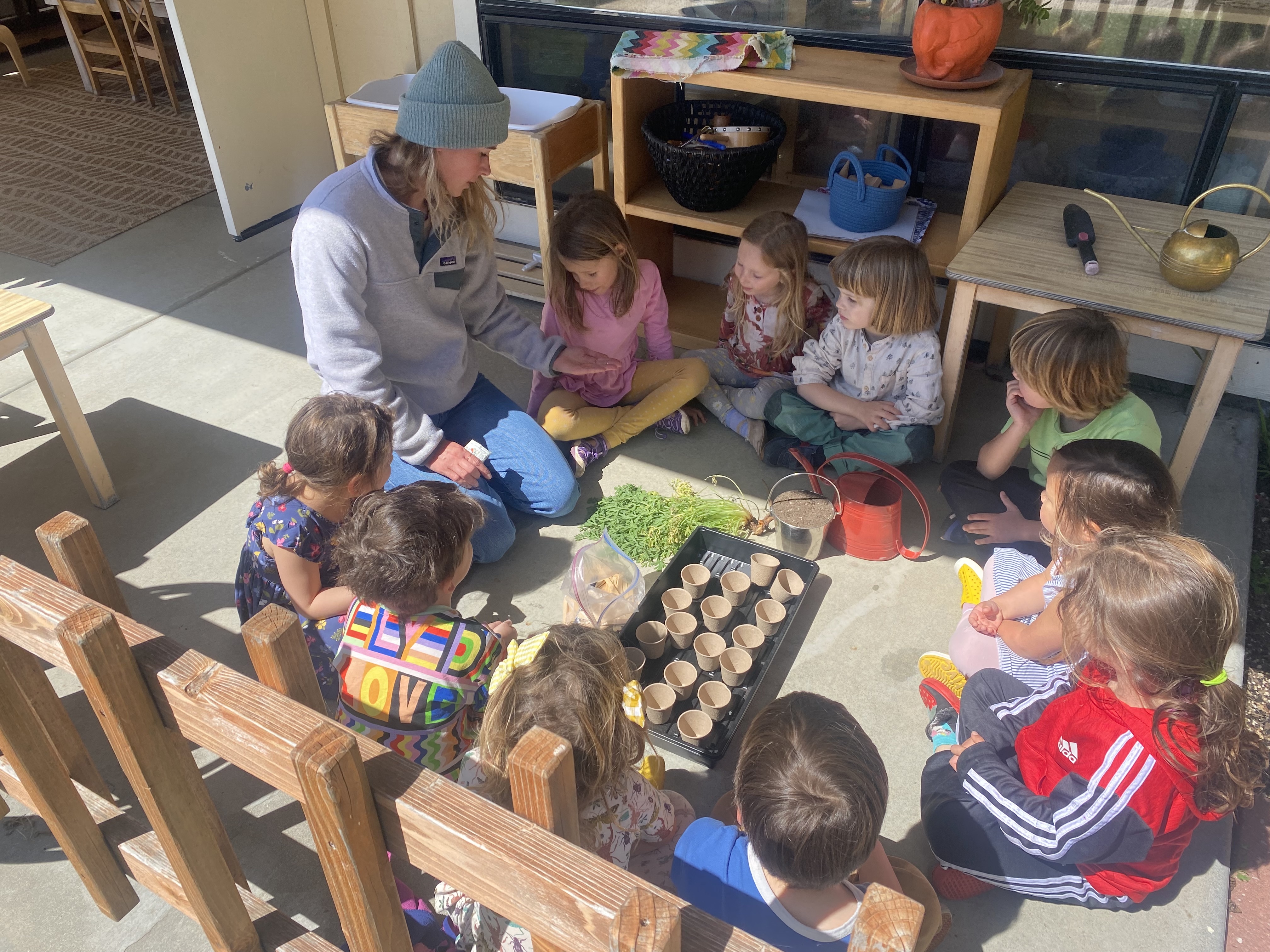A group of Montessori children are sitting in a circle with a guide.