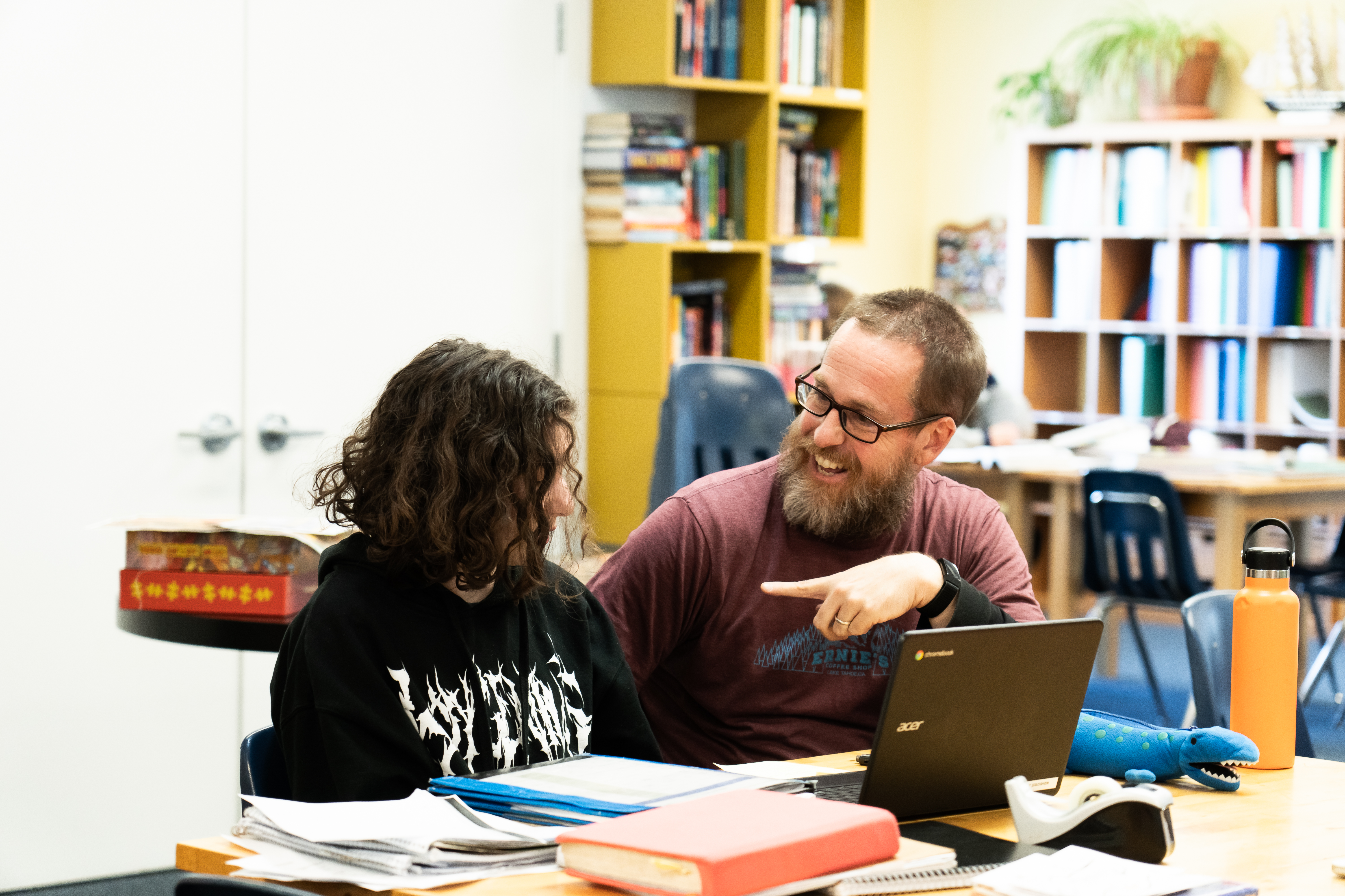 A Montessori guide and a child are sitting at a table with a laptop.
