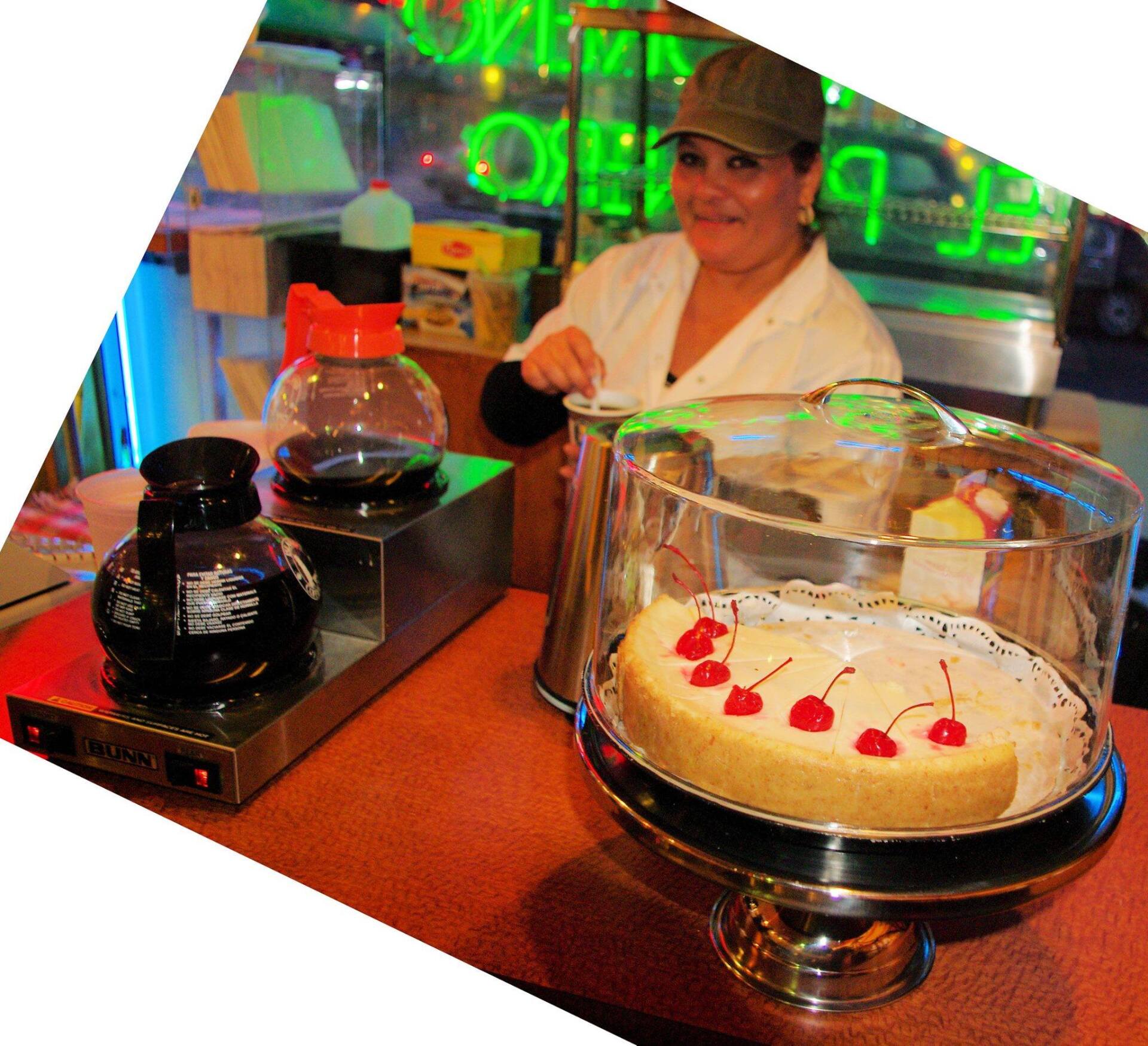 A woman stands behind a counter with a cake on it
