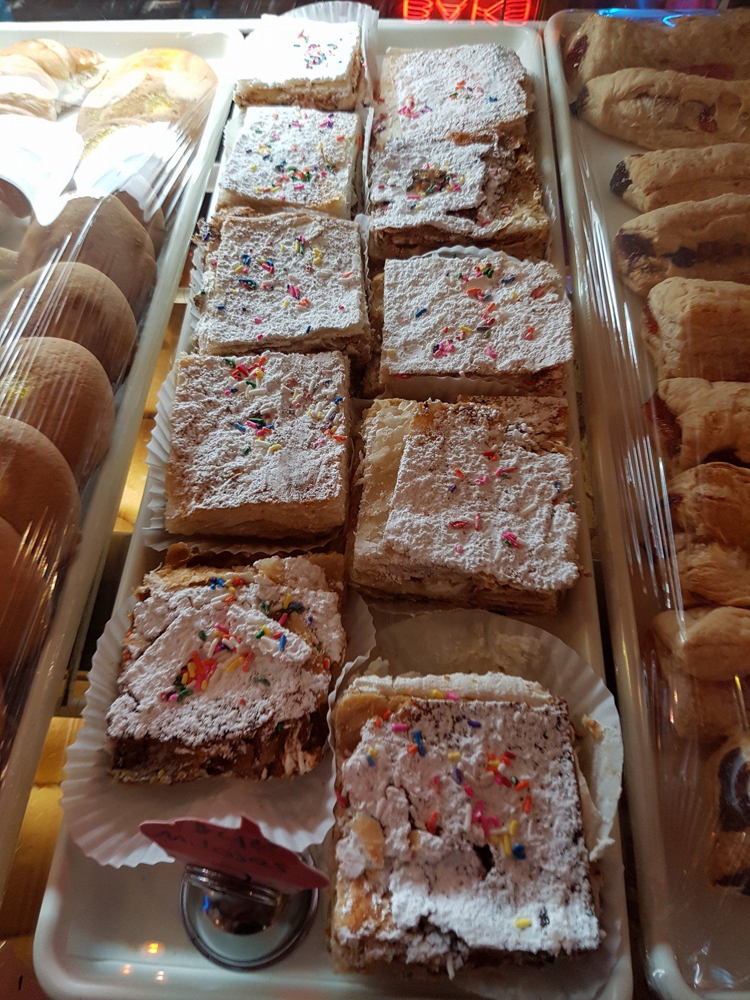 A tray of pastries with powdered sugar and sprinkles on them.