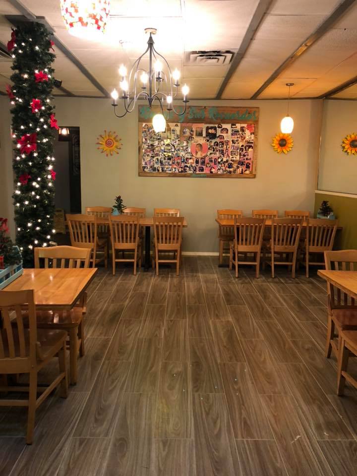 A restaurant with tables and chairs and a christmas tree on the wall.