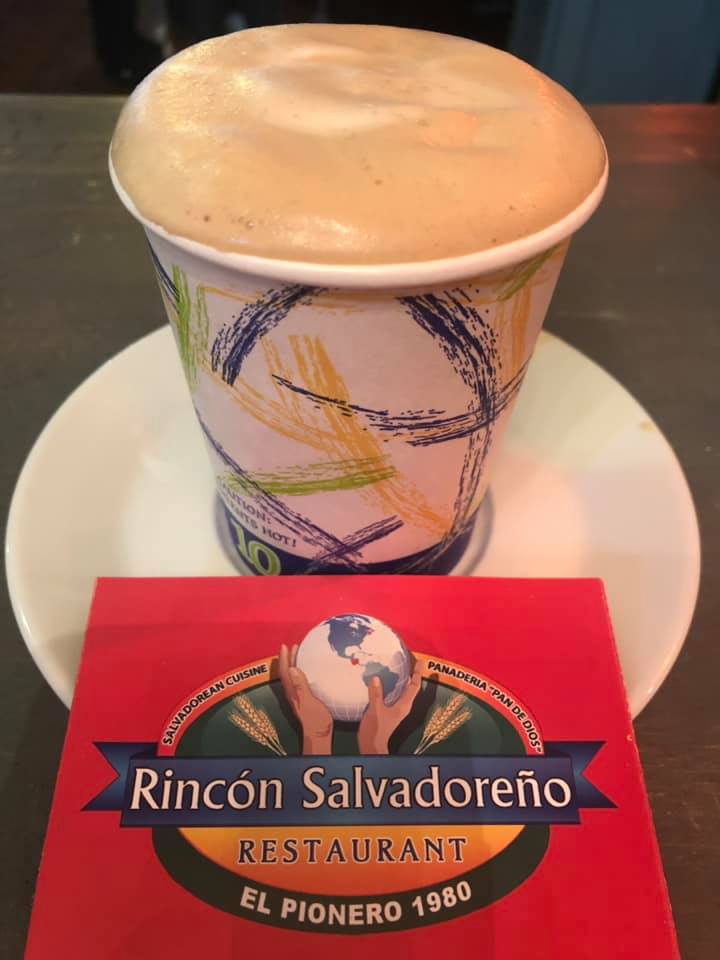 A cup of coffee sits on a saucer next to a card for rincon salvadoreno restaurant