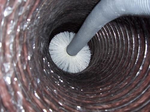 A person is cleaning a duct with a brush.