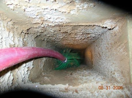 A person is cleaning a chimney with a green brush.