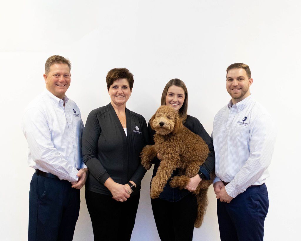 A group of people standing next to each other holding a dog.