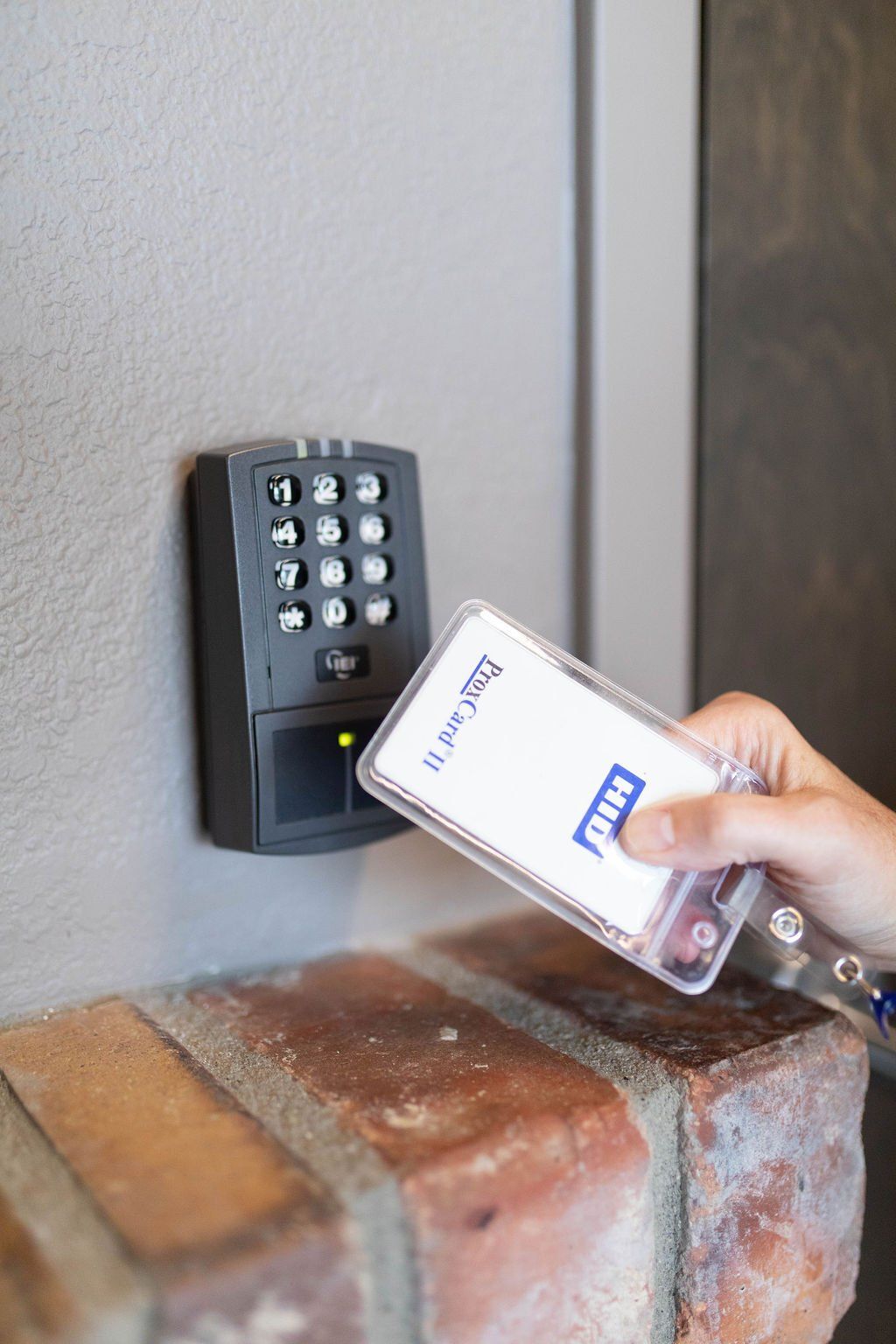 A person is holding a card in front of a keypad.