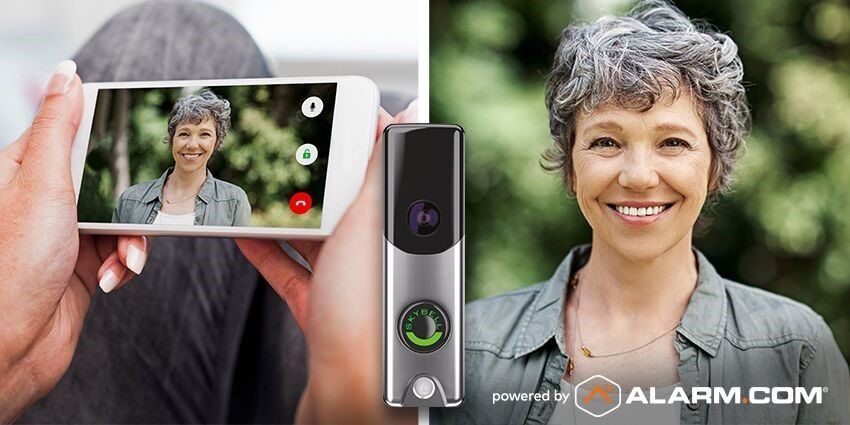 A woman is holding a cell phone next to a doorbell.