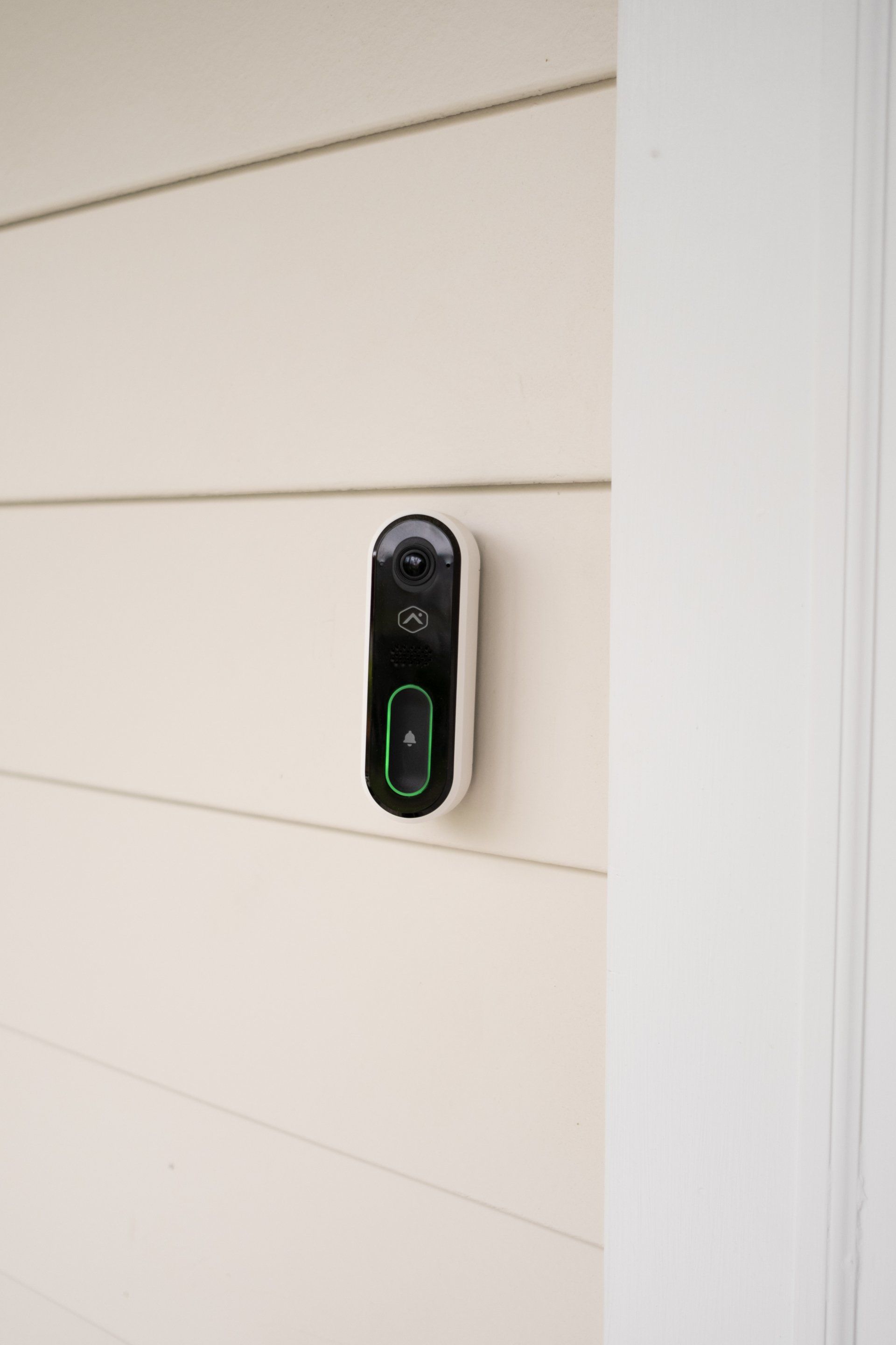 A doorbell is hanging on the side of a house.