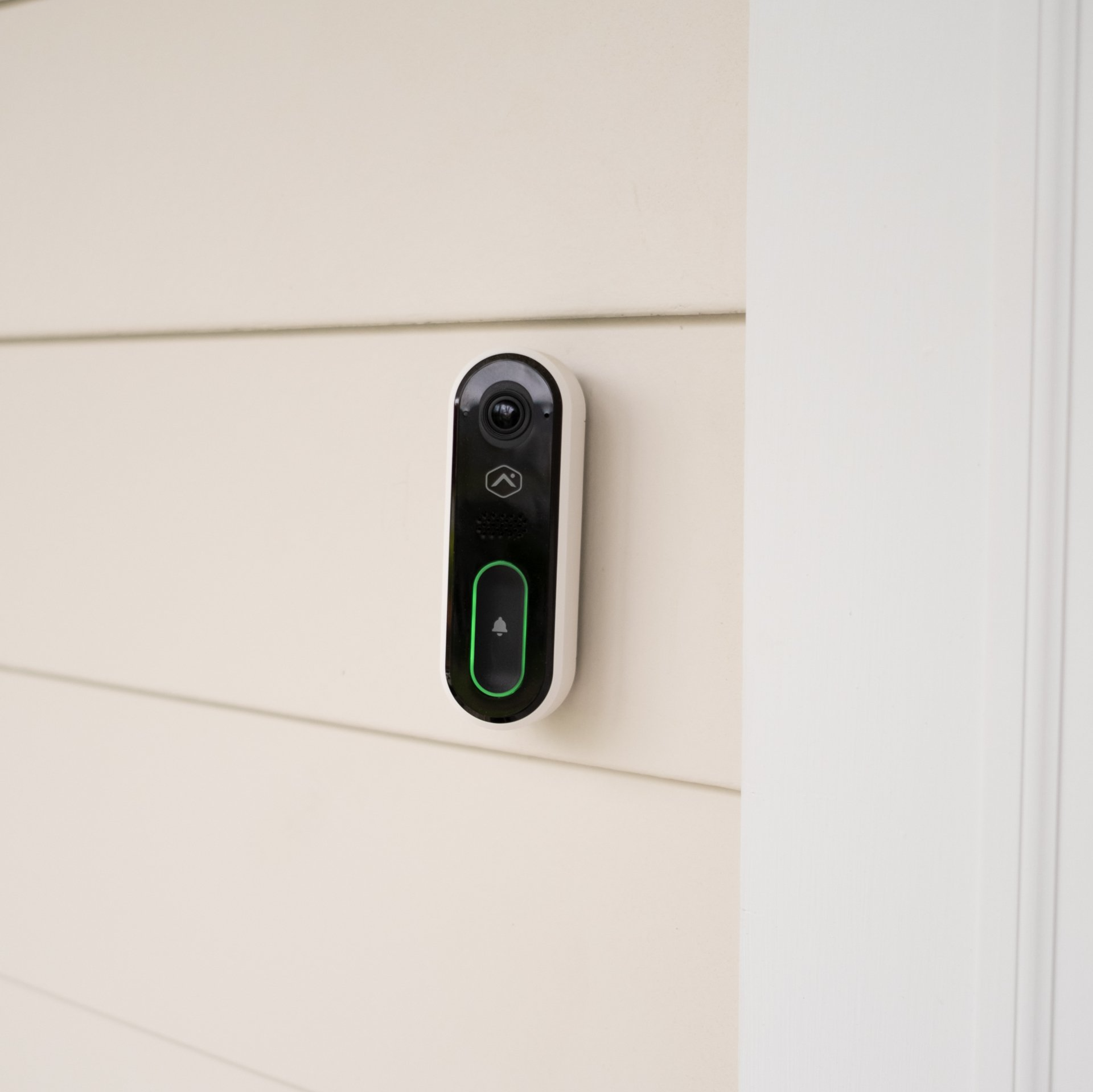 A doorbell is hanging on the side of a house.