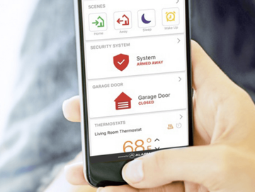 A person is holding a smart phone with a security system app on it