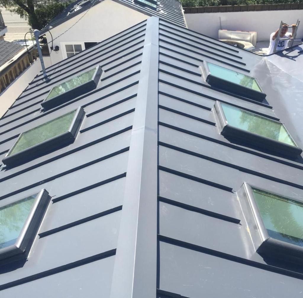 Aerial view of a gray metal roof with skylights and a central ridge line