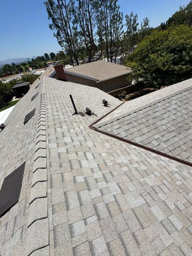 Worker installing red roof tiles on a house rooftop under a cloudy sky