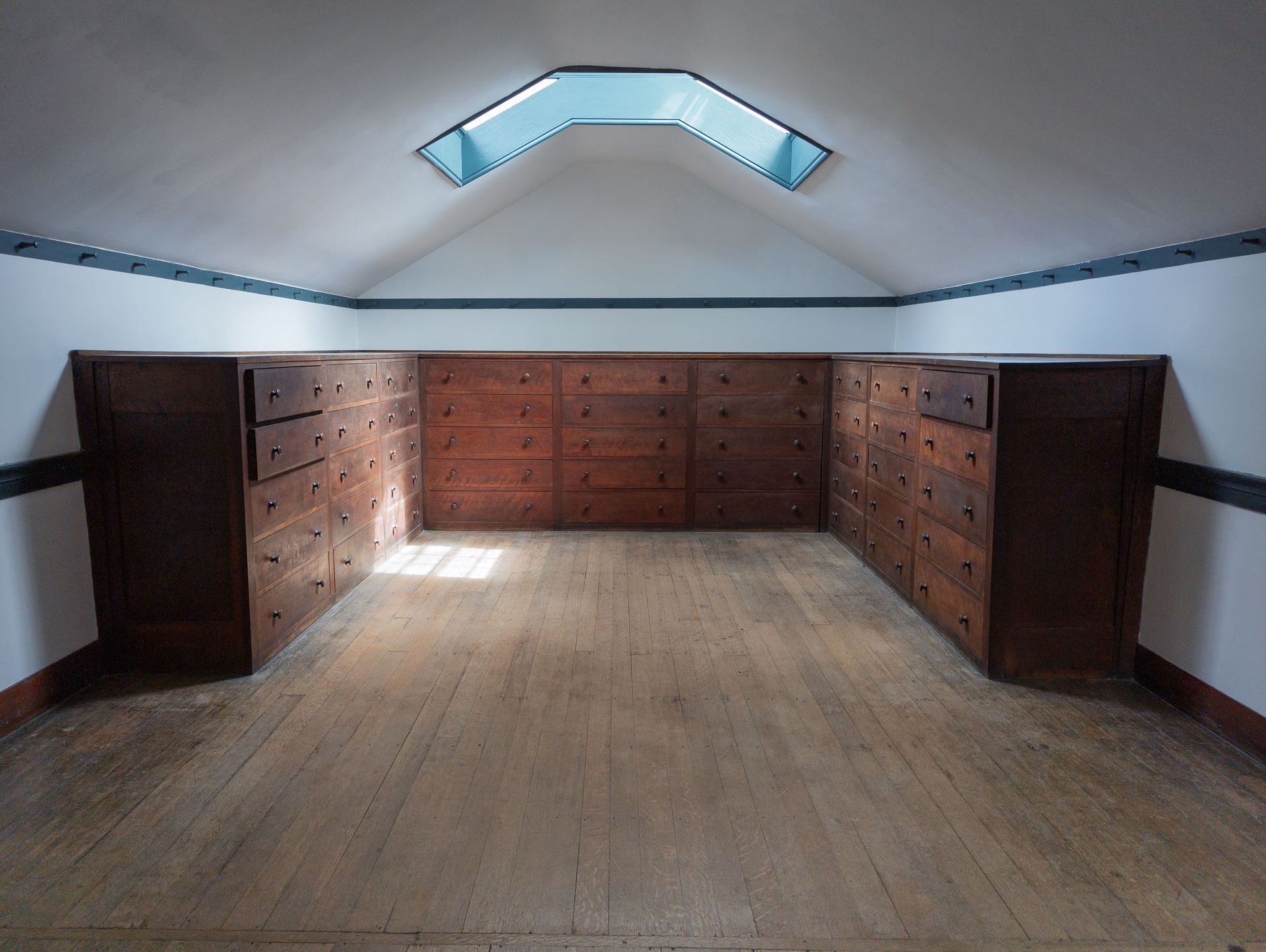 Empty room with built-in wooden cabinets and a skylight on a sloped ceiling.
