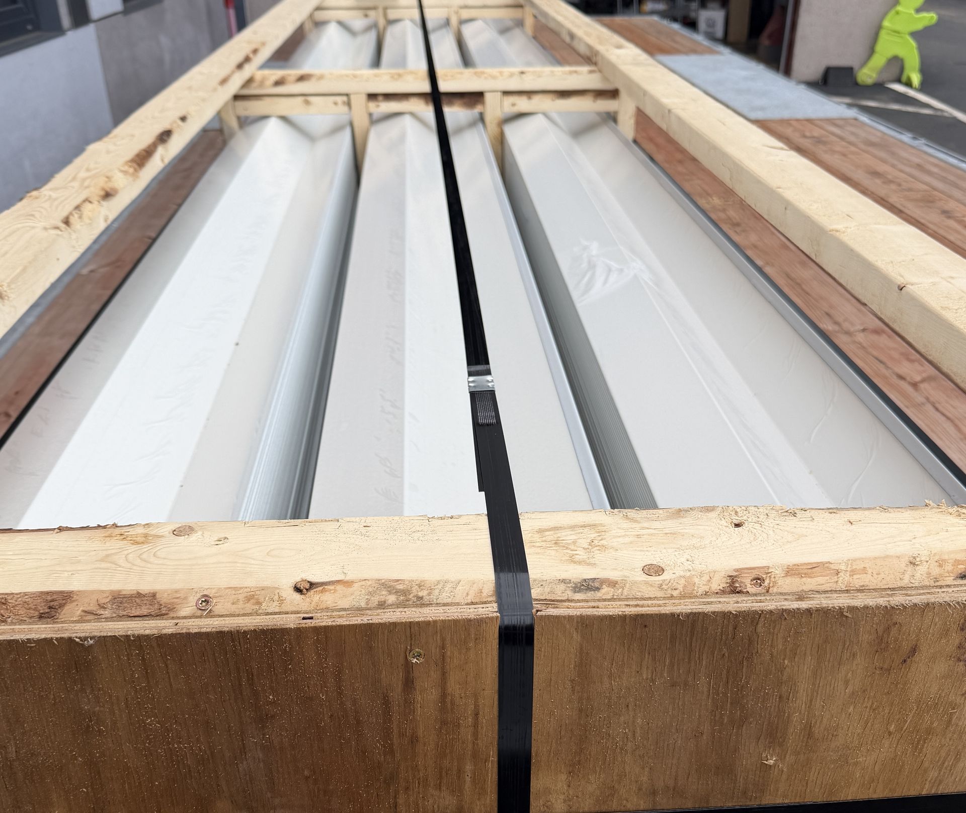 Long formed louver blades supported inside a wooden crate.