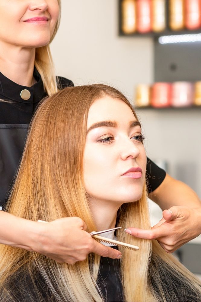 A woman is practicing how to cut a woman's hair.