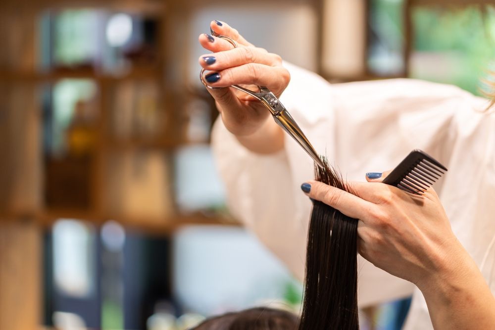 A woman is getting her hair cut by a hairdresser in a salon.
