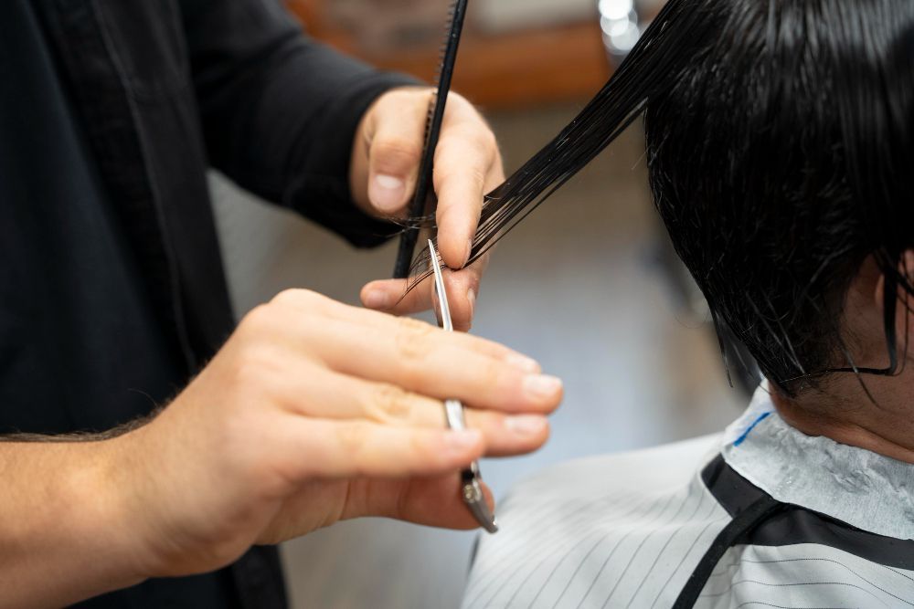 A man is getting his hair cut by a barber.