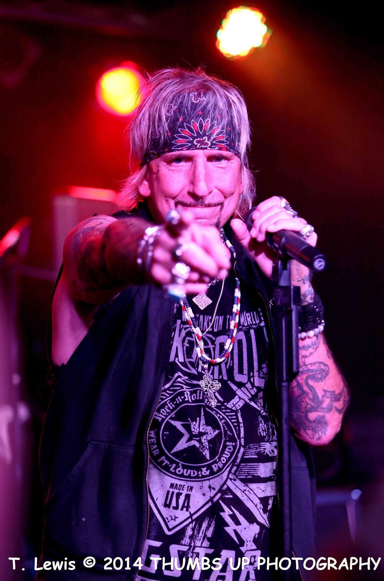 A man is pointing at the camera while singing into a microphone.