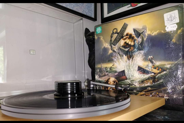 A record player with a record on it and a picture on the wall behind it.