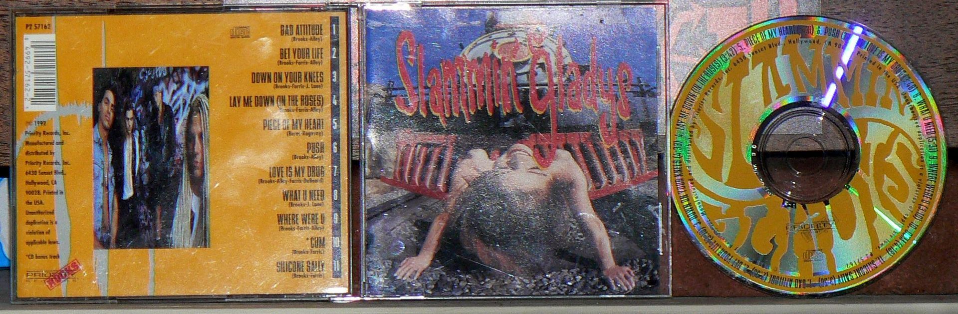 Three cd 's are lined up on a shelf one of which has a picture of a woman on it