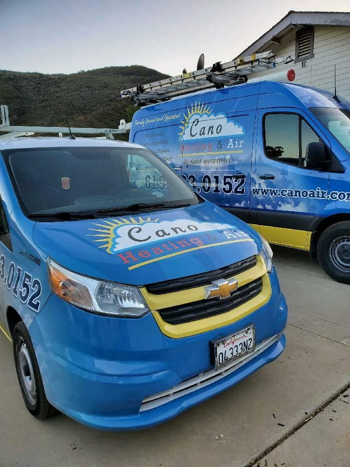 Two blue Cano Heating & Air service vans parked outside. One Chevrolet, one Mercedes-Benz, with ladders.