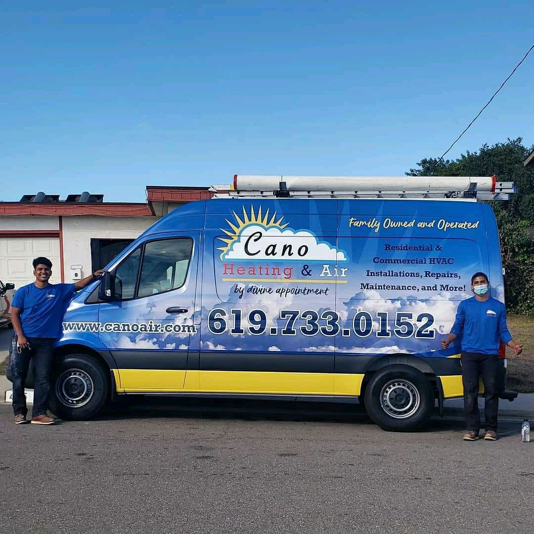 Two men stand with a blue van labeled 