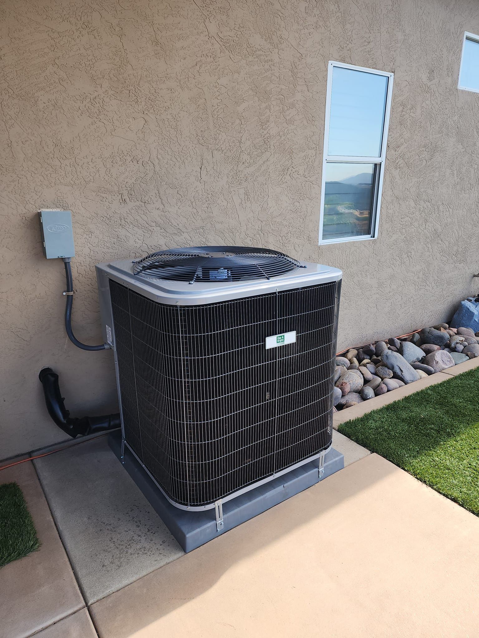 Air conditioning unit outside a building, on a concrete pad.