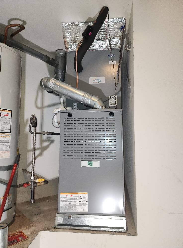Furnace and water heater in a utility closet with vent pipes and ductwork.