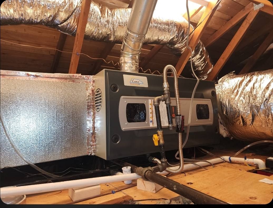 HVAC unit in an attic with ductwork, insulation, and exposed wooden beams.