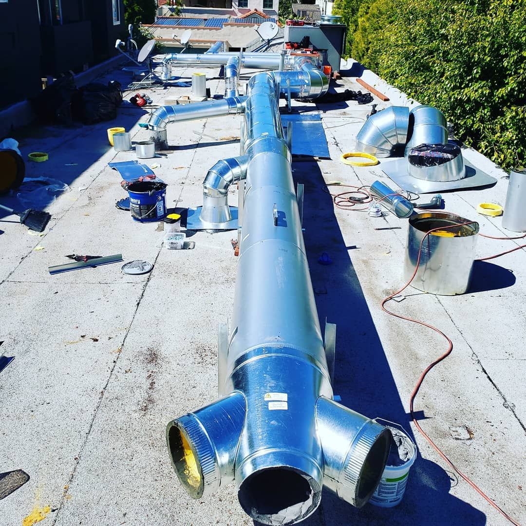 Ventilation system components on a rooftop, including ducts, fittings, and cans.