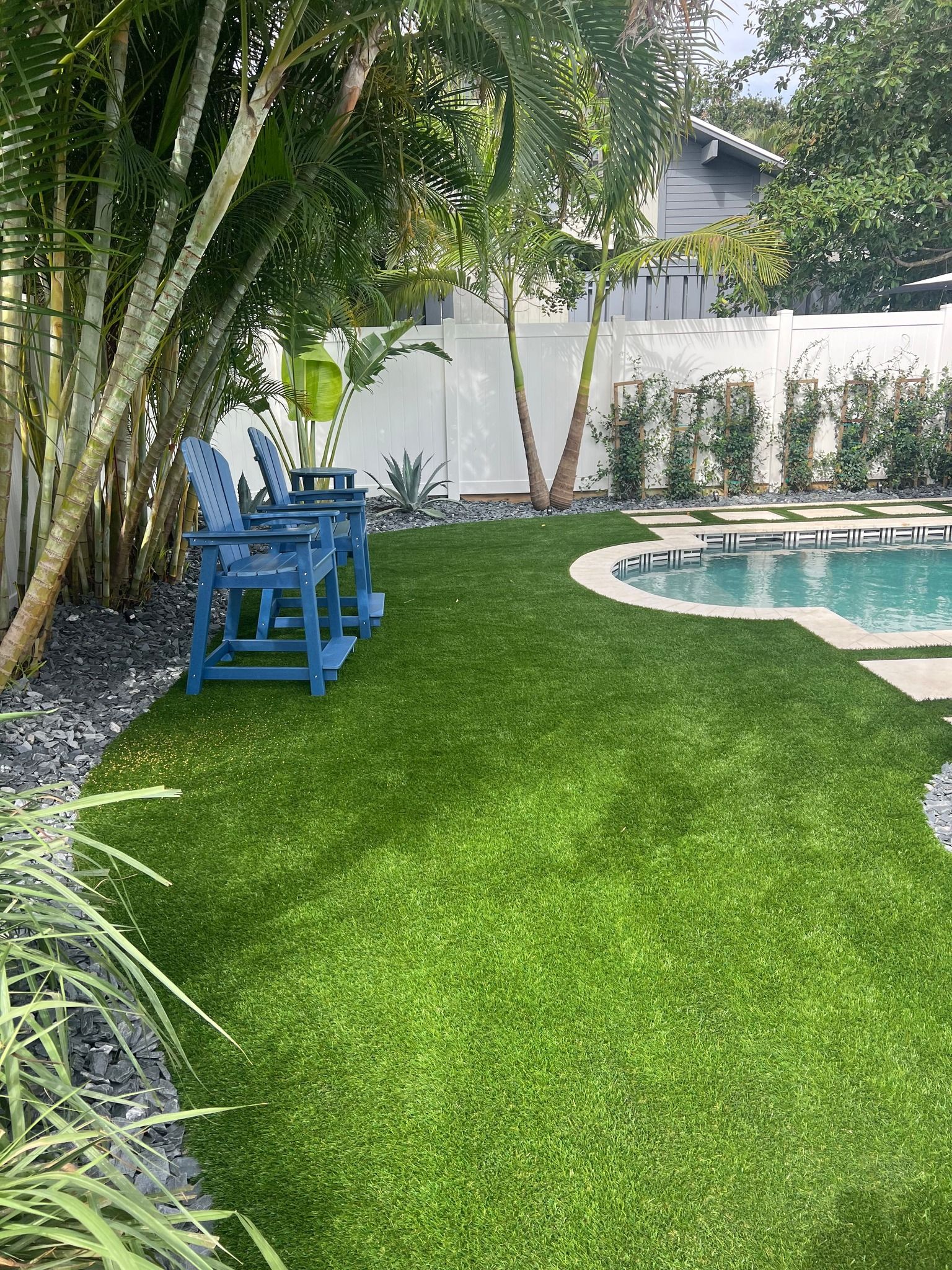 Lush green lawn next to a black fence and gate, sunny day.