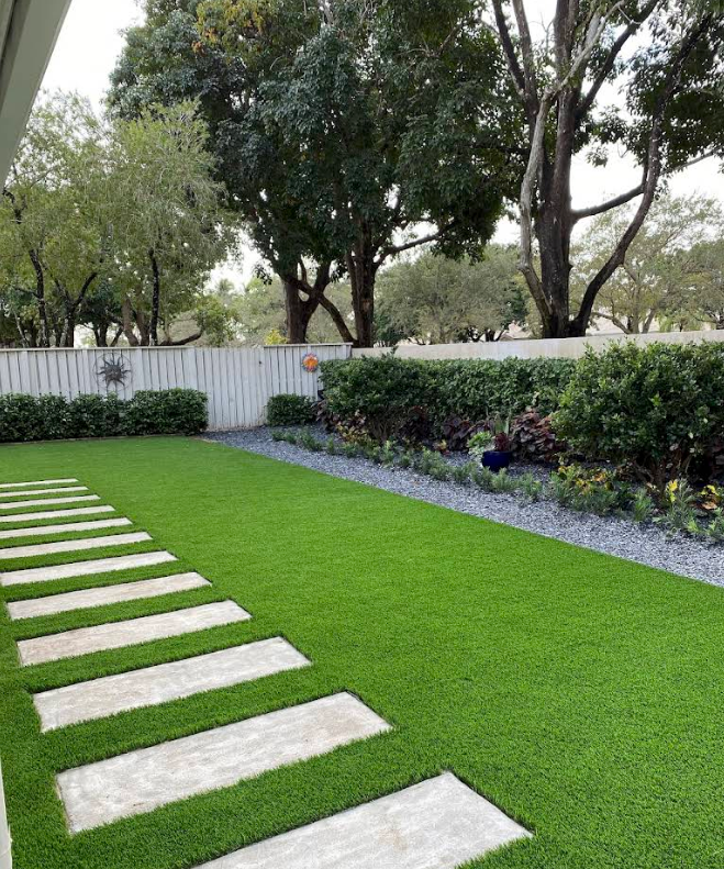 Stepping-stone path through a bright green lawn beside shrubs and trees in a landscaped yard.