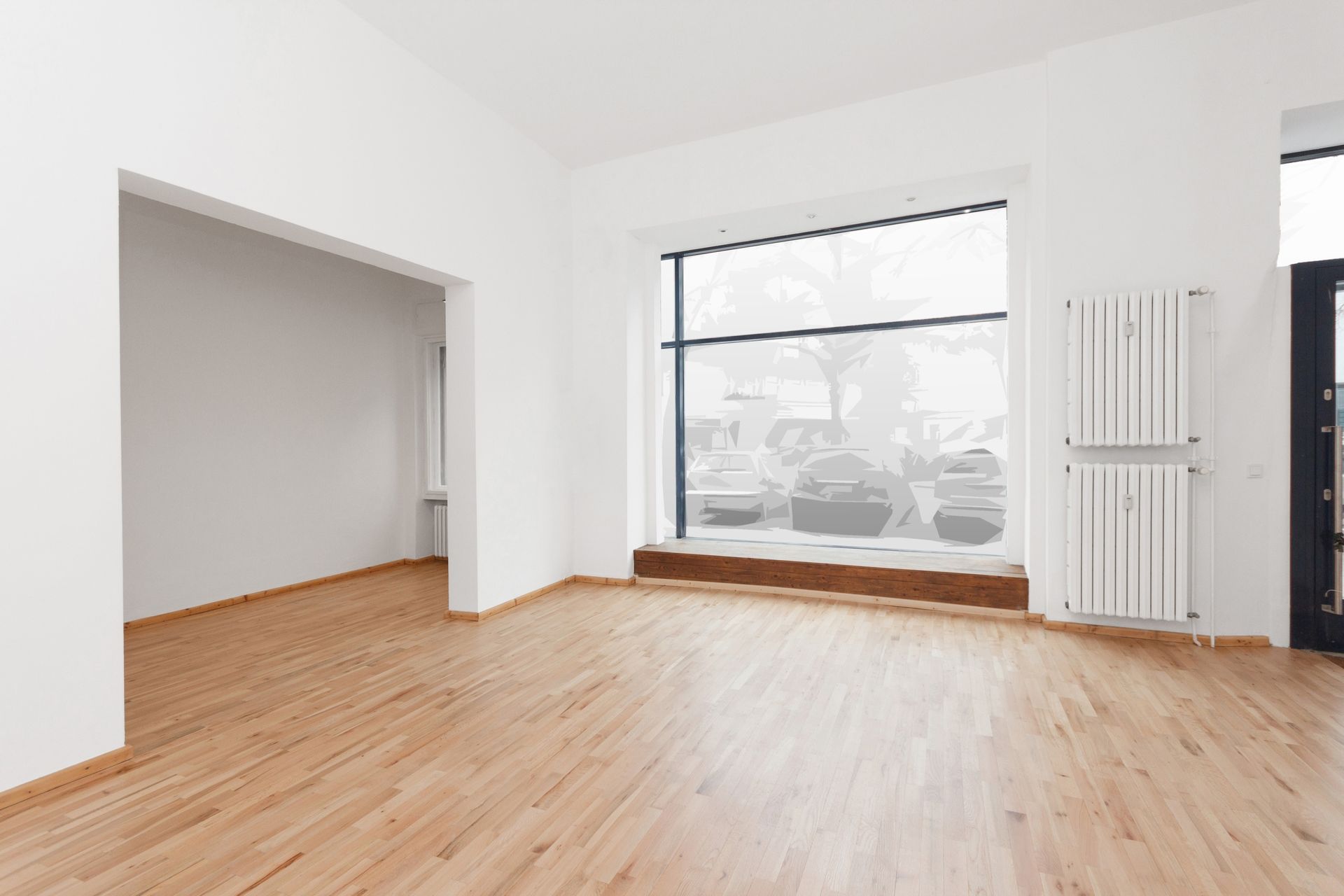 An empty room with wooden floors and a large window.