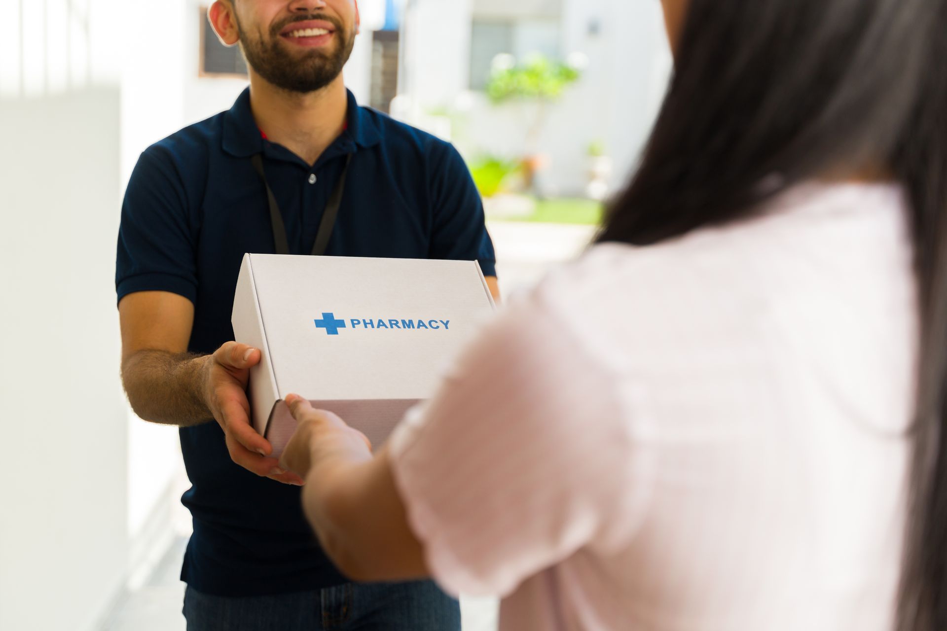 Courier handing a pharmacy delivery box to a customer at the door.