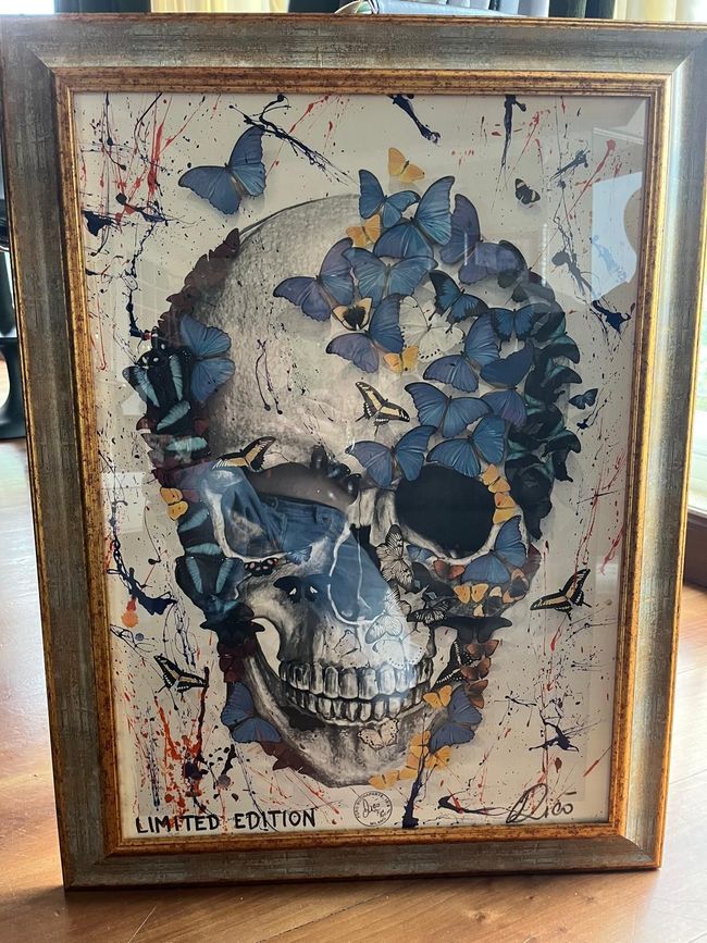 Dipinto astratto con audaci blocchi di blu, arancione e nero, che presenta testo e forme geometriche su una parete bianca della galleria.