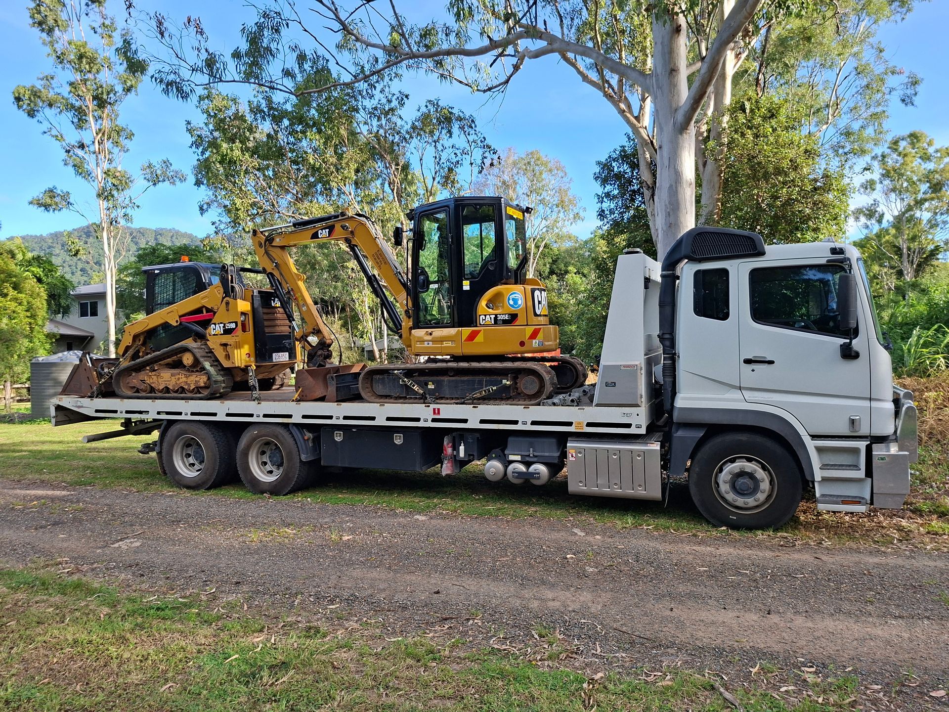 A Semi Truck is Driving Down a Highway Next to a Field — Airlie Towing & Tilt Tray Hire In Cannonvale, QLD