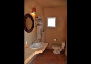 A bathroom with a sink , toilet , mirror and window.