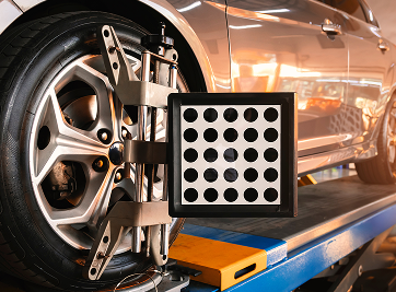 Car wheel with alignment equipment; wheel on lift, black and white target, silver metal tools. | Zee's Alignment & Autocare