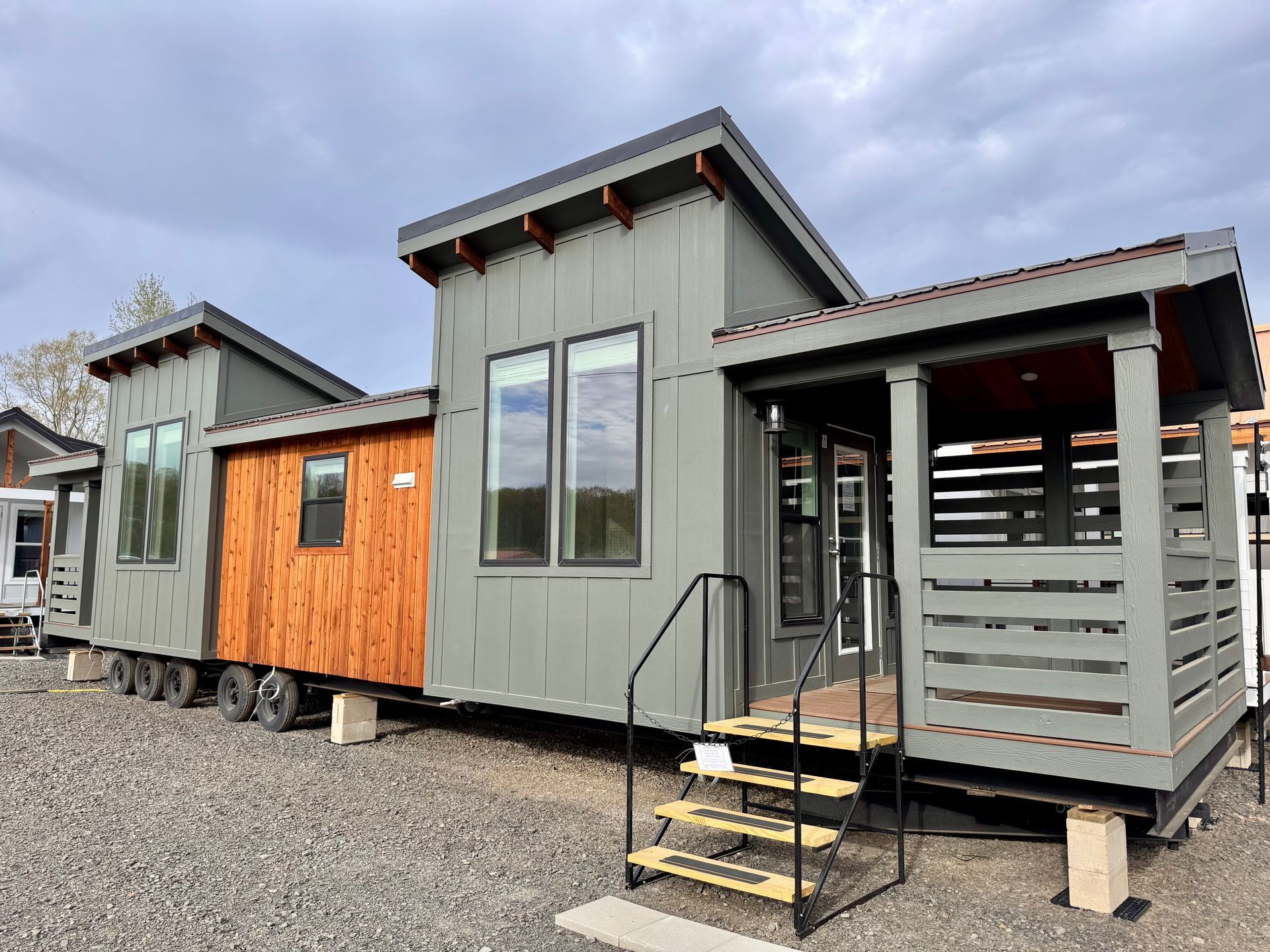 Modern tiny house with gray and wood siding, porch, and steps.