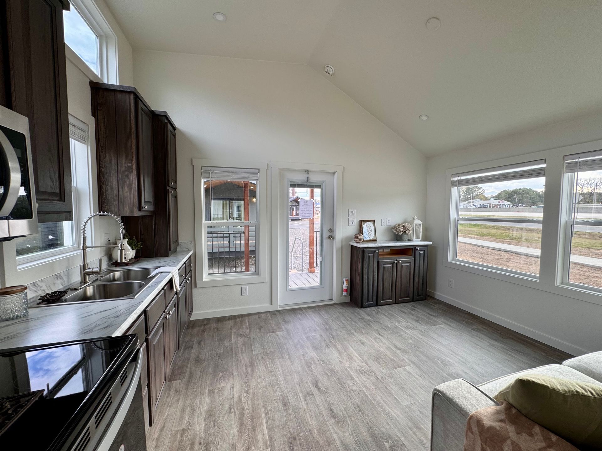 An open-concept room with a kitchen on the left, a glass-paneled door, and windows overlooking a parking lot.