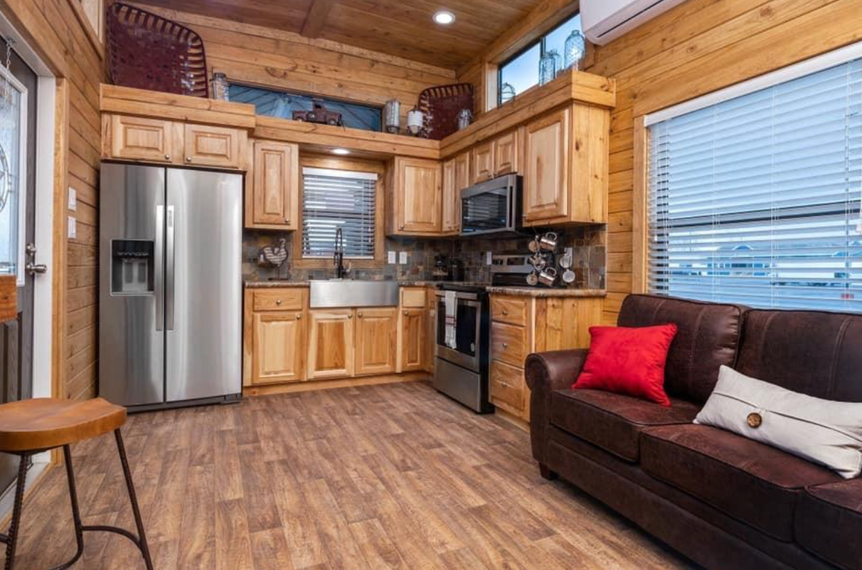A living room with a couch and a kitchen in a tiny house.